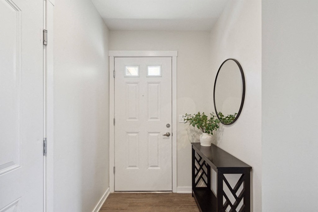 a hallway with a white door and a dresser with a vase on it