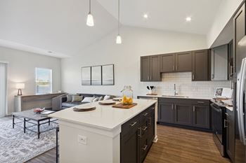 a kitchen and living room with a white counter top and dark cabinets