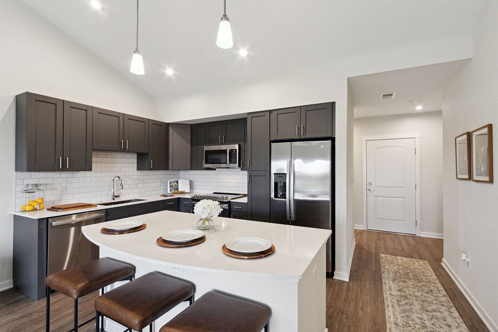 a kitchen with black cabinets and a white island with chairs