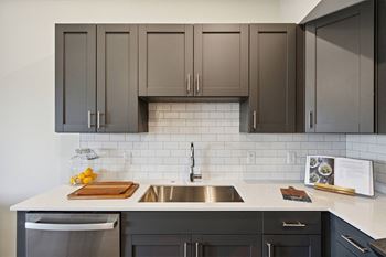 a kitchen with gray cabinets and a white counter top and a sink