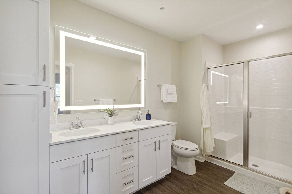 a white bathroom with a large mirror and a shower