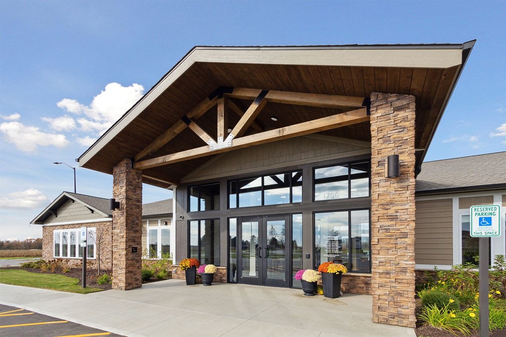 the front of a building with large glass windows and a roof