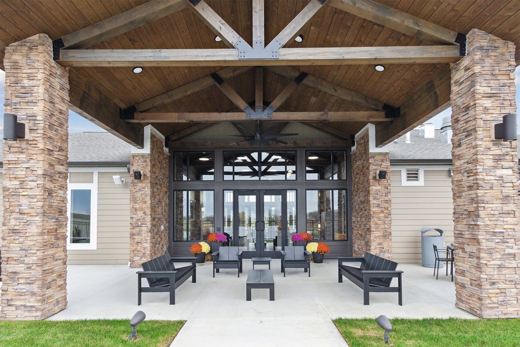 a covered patio with chairs and a large building