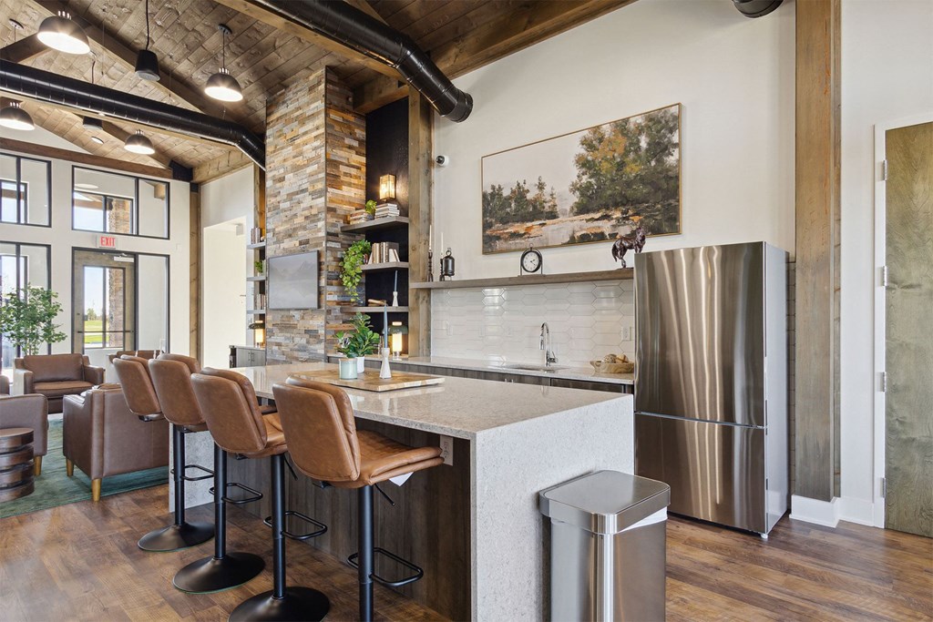 a kitchen with a bar and chairs and a refrigerator