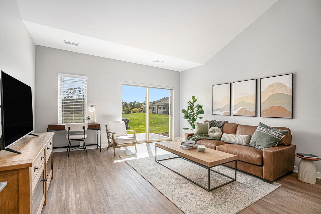 A living room with a brown couch, a wooden table, and a flat screen TV.