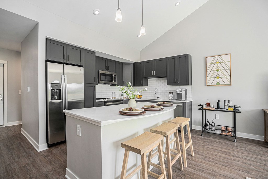 A kitchen with a white island and wooden bar stools.