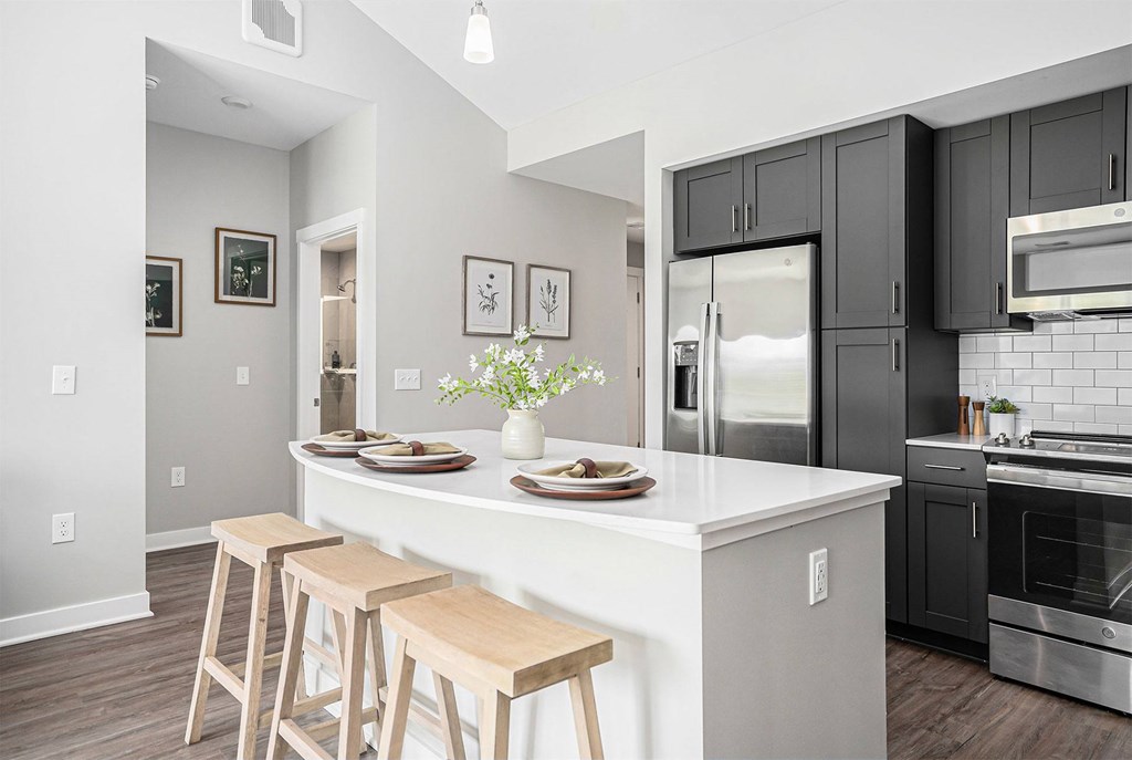 A kitchen with a white island and black cabinets.