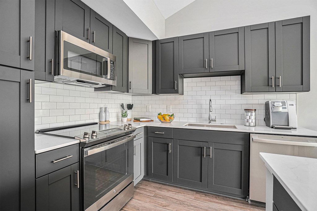 A kitchen with black cabinets and a white backsplash.