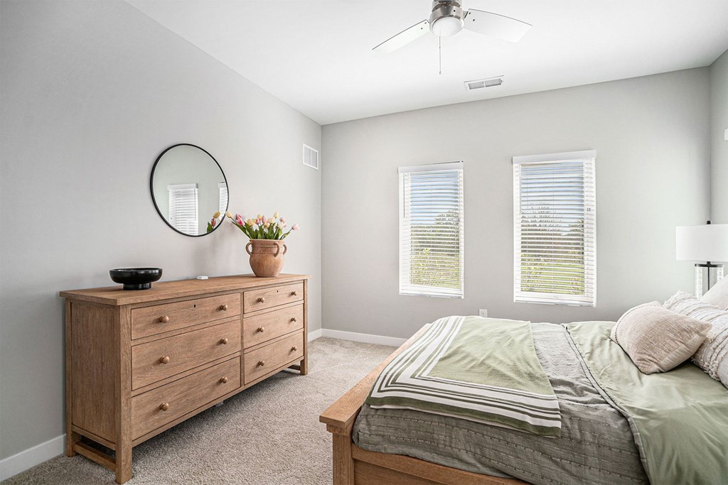 A bedroom with a bed, dresser, and window.