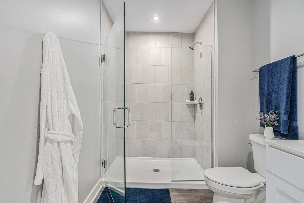 A white bathroom with a towel hanging on the wall.
