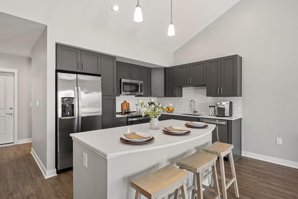 a kitchen with a large island and a stainless steel refrigerator