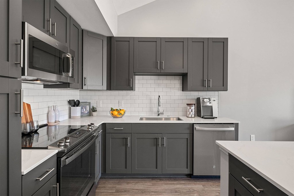 a kitchen with black cabinets and white counters and a sink