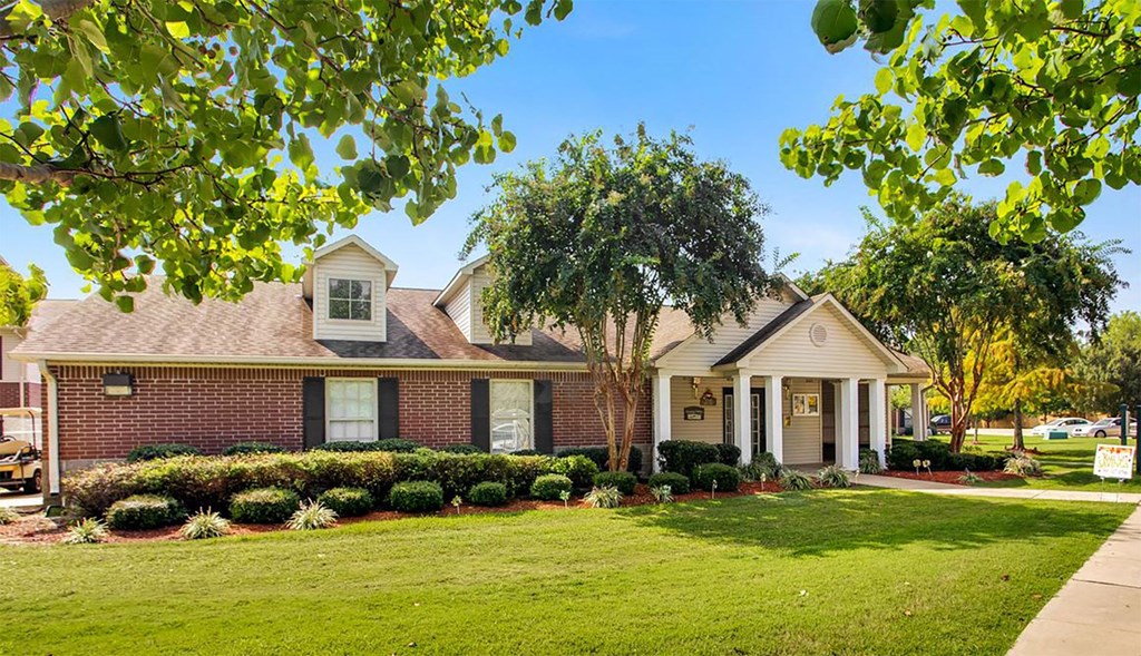 A house with a well-manicured lawn and a tree in front.