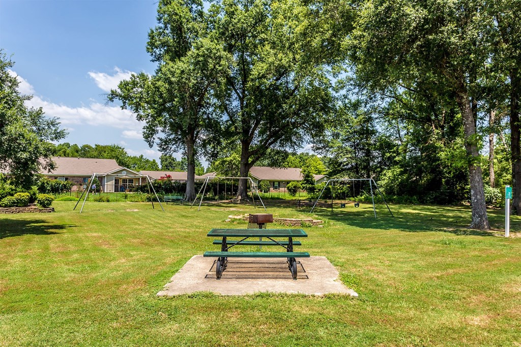 A green picnic table sits in the middle of a grassy field.