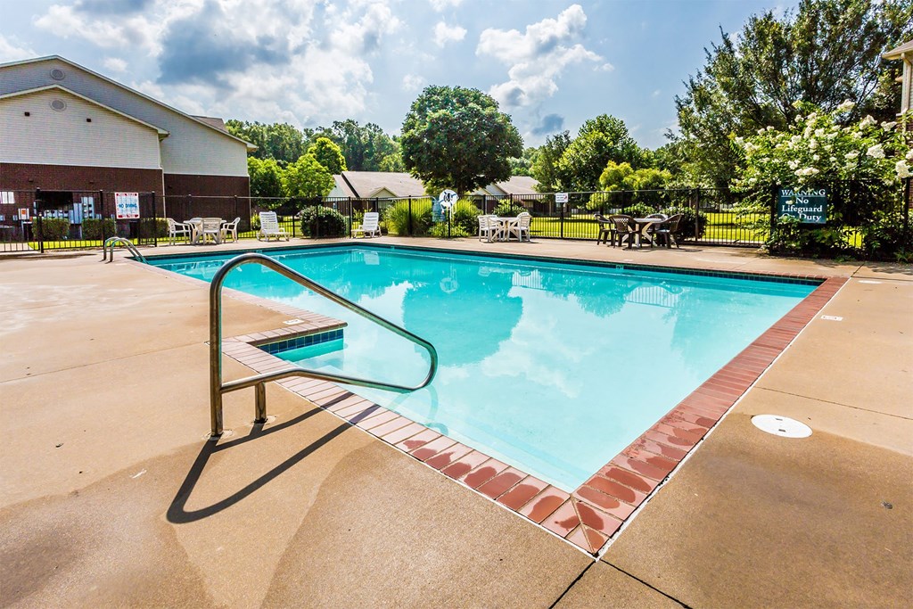 A large outdoor swimming pool with a red brick border.