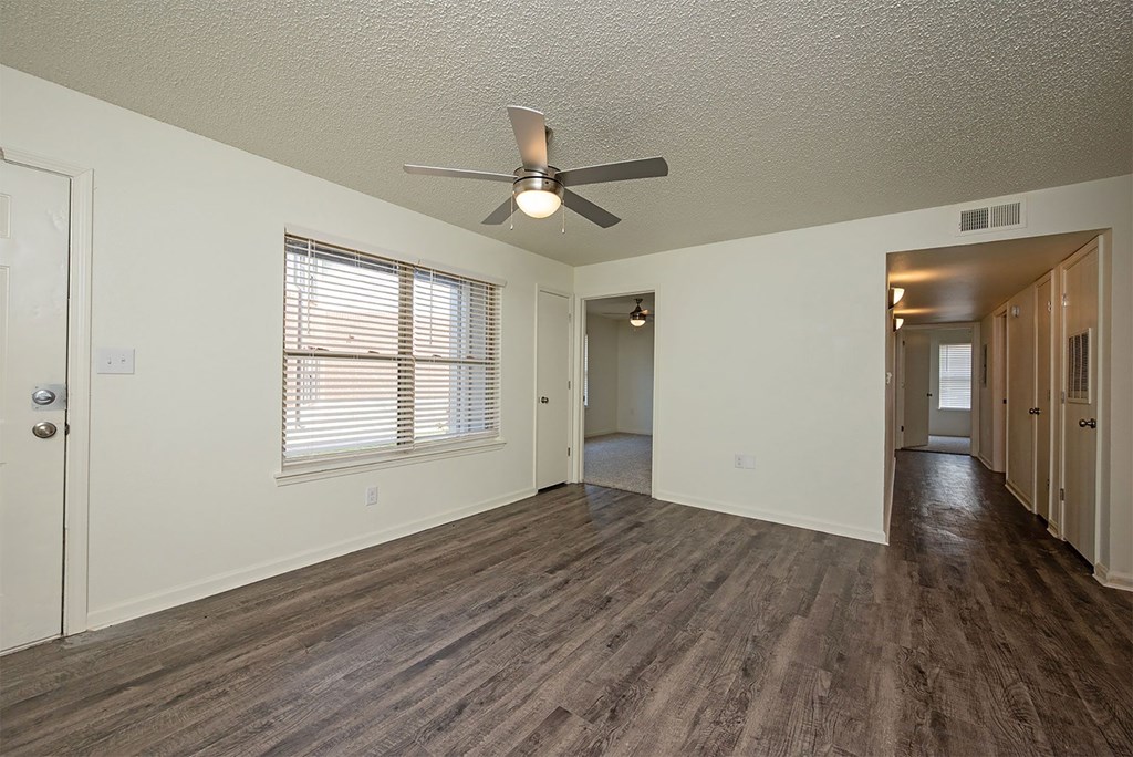A room with a ceiling fan and wooden flooring.