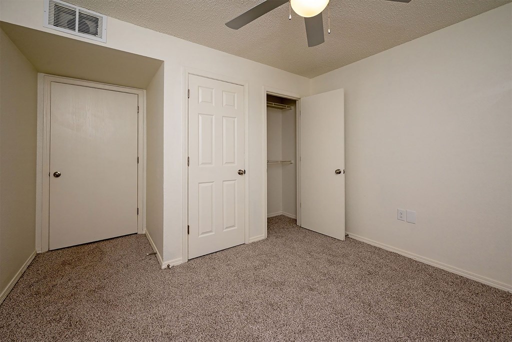 A room with carpeted floor and three doors.