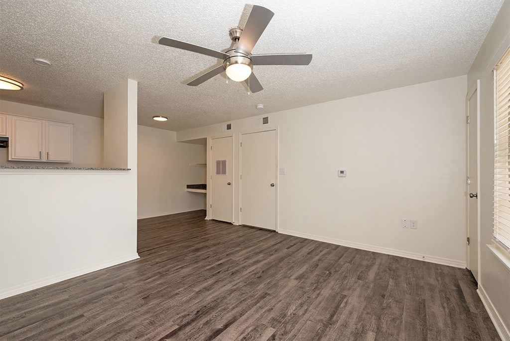 A room with a ceiling fan and wooden flooring.