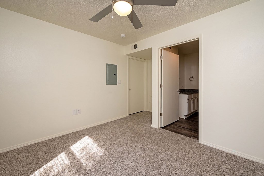 A room with a ceiling fan and a doorway leading to another room.