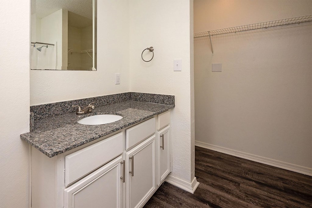 A bathroom with a granite countertop and white cabinets.