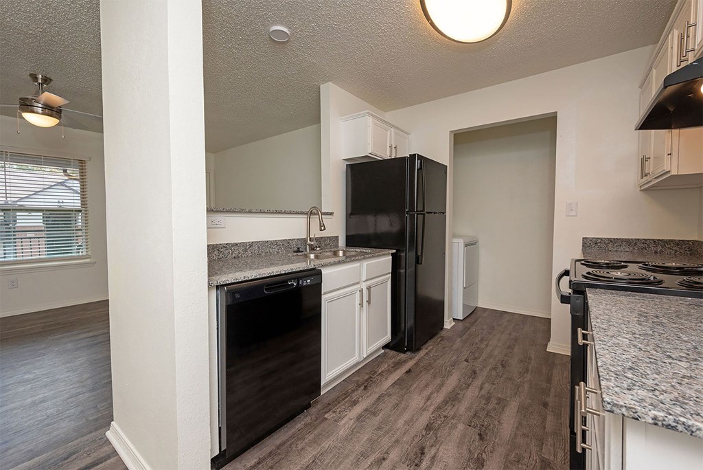 A kitchen with a black refrigerator and a marble countertop.