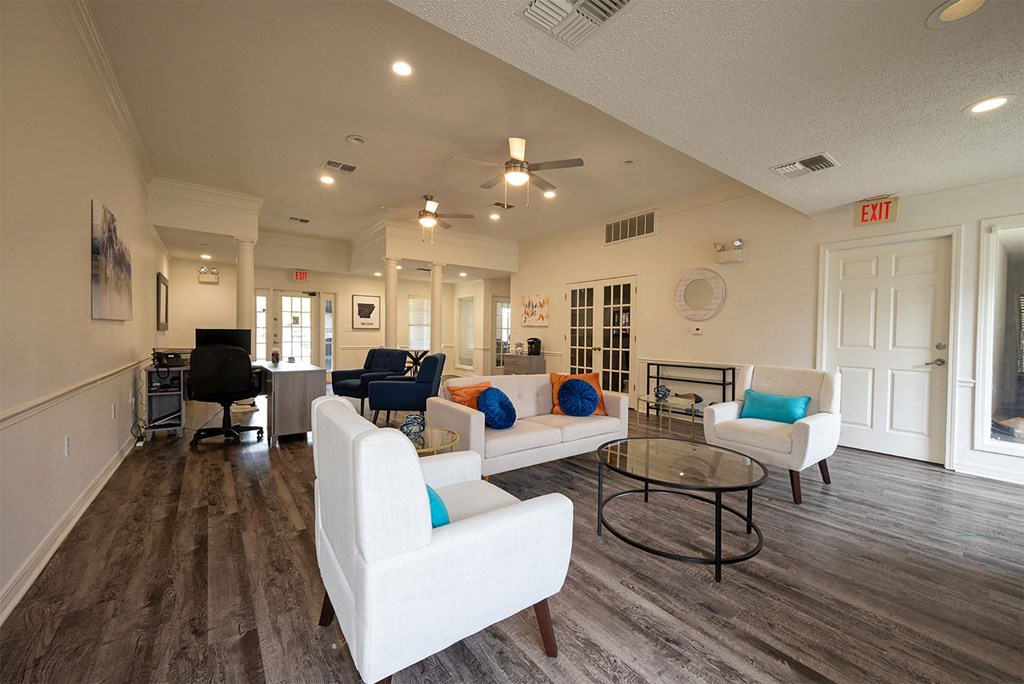 A spacious living room with white furniture and a ceiling fan.