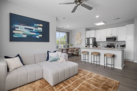 A modern living room with a grey sofa and a painting on the wall.