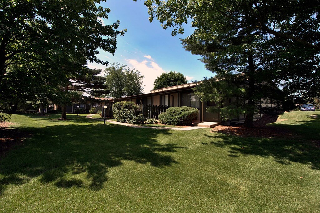A house with a lawn and trees in front of it.