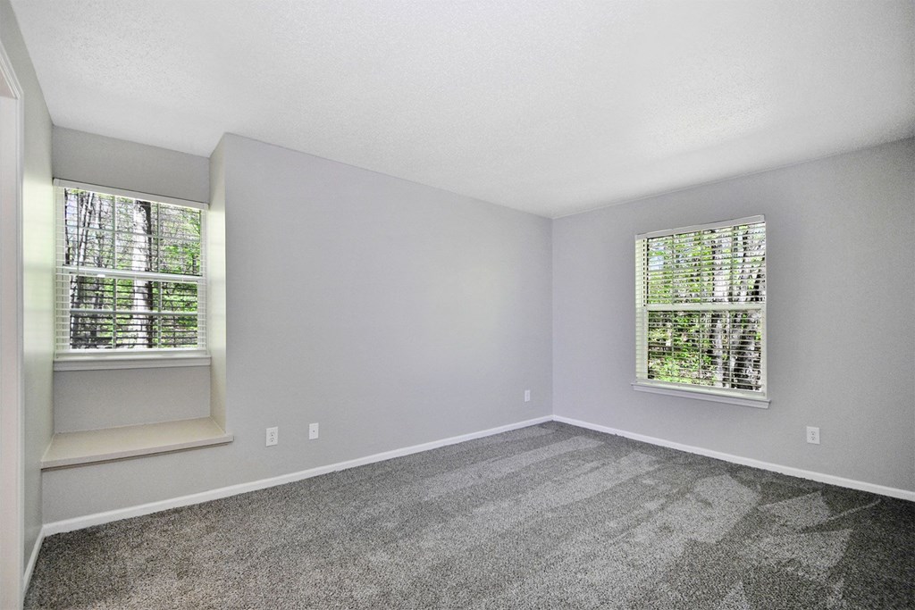 an empty room with carpet and two windows