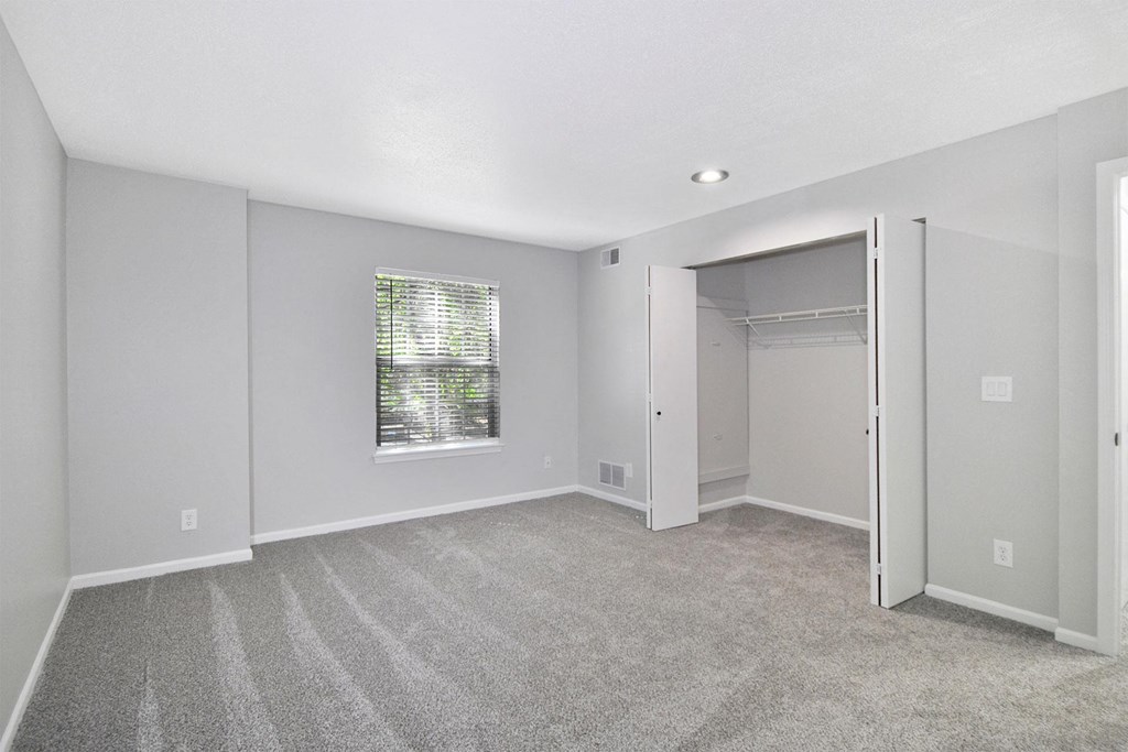 an empty bedroom with a closet and a window