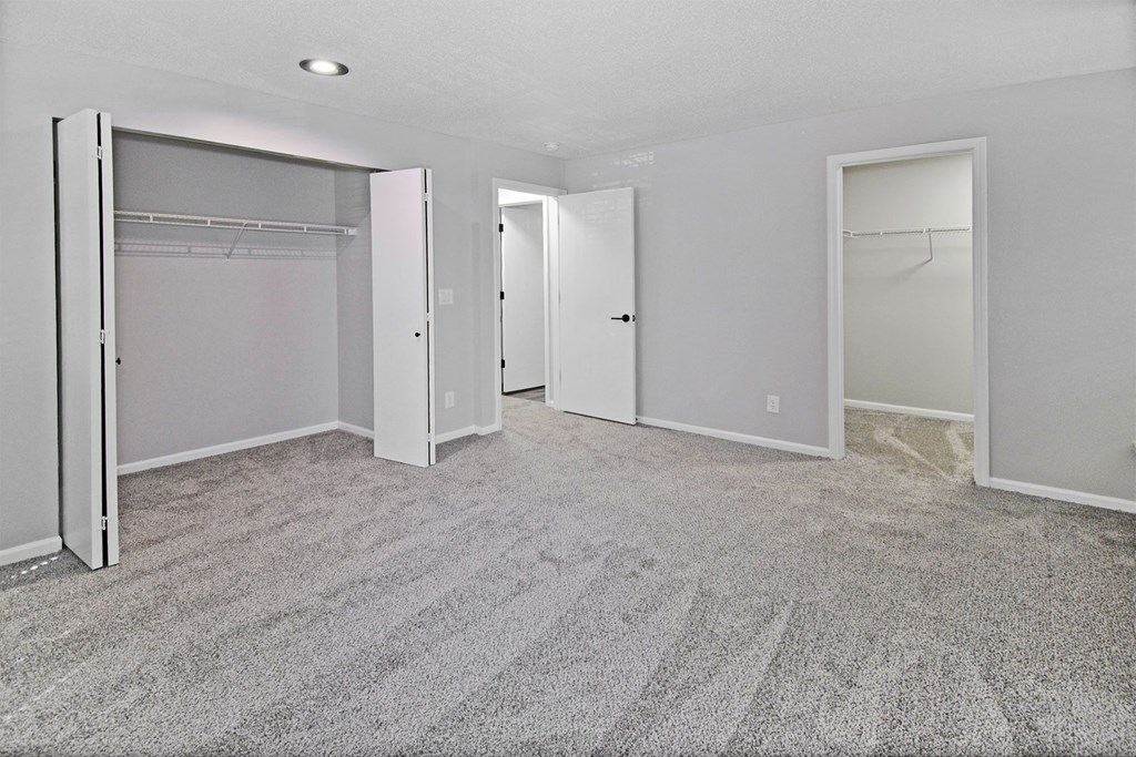 an empty room with white closet doors and a carpeted floor