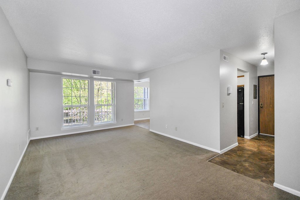 the living room and dining room of an empty house with a large window