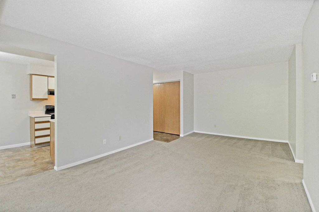 the spacious living room and kitchen of an apartment