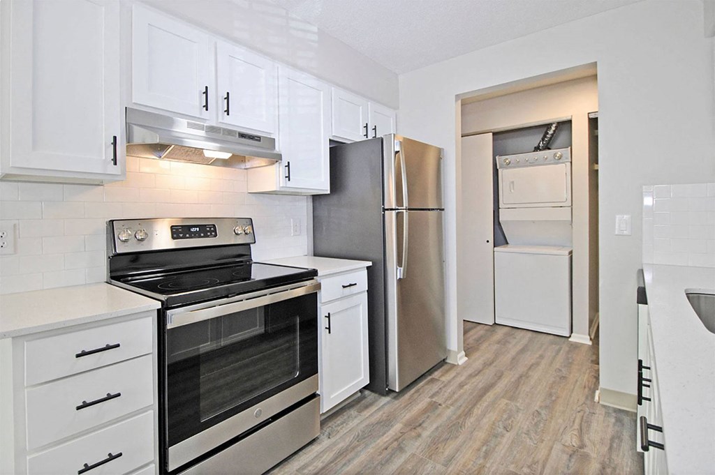 A kitchen with white cabinets and a stainless steel refrigerator.