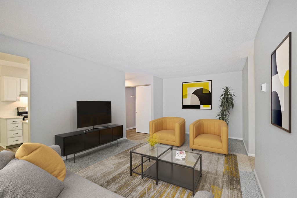 A living room with a grey couch, a yellow chair, a black coffee table, and a TV.