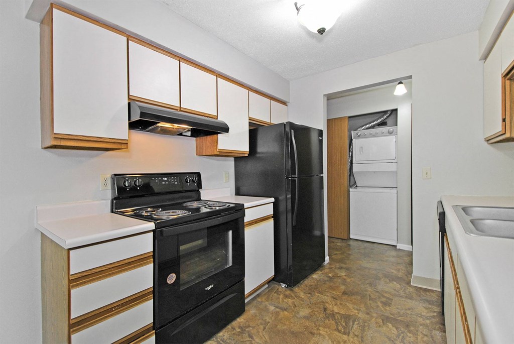 A kitchen with black and white appliances and wooden cabinets.