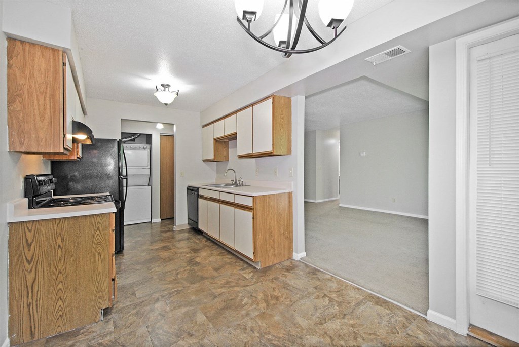 A kitchen with wooden cabinets and a black refrigerator.
