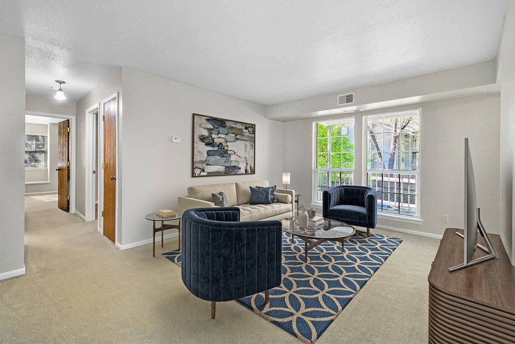 A living room with a blue chair and a painting on the wall.