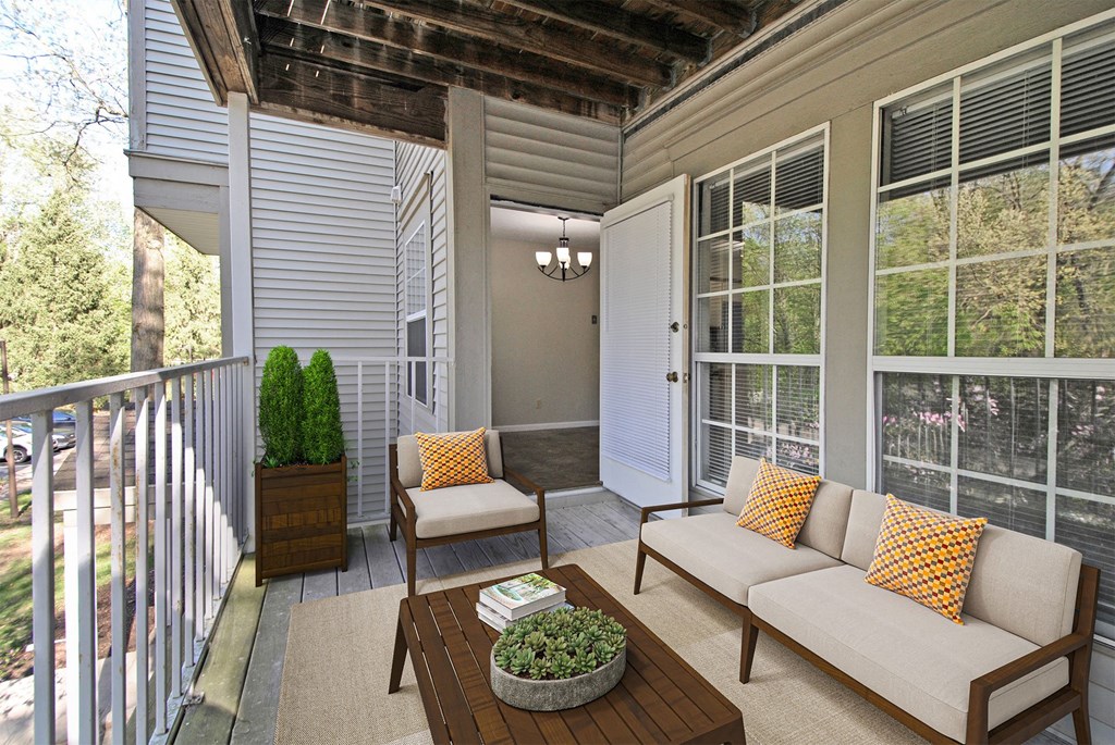 A white house with a wooden porch and a couch with orange pillows.