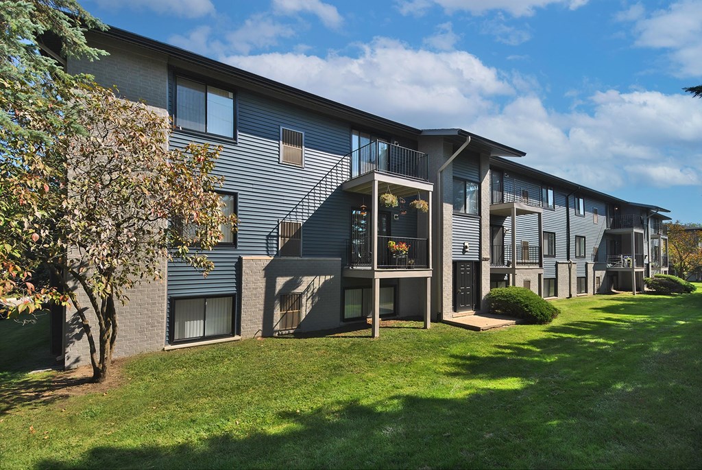 A modern apartment building with a tree in front.
