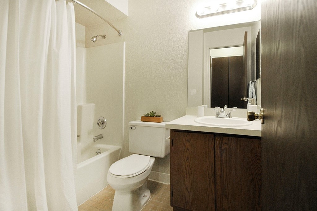 A white toilet sits next to a white sink in a small bathroom.