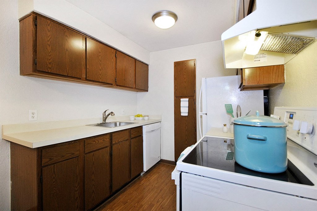 A kitchen with a white fridge and a blue pot on the stove.