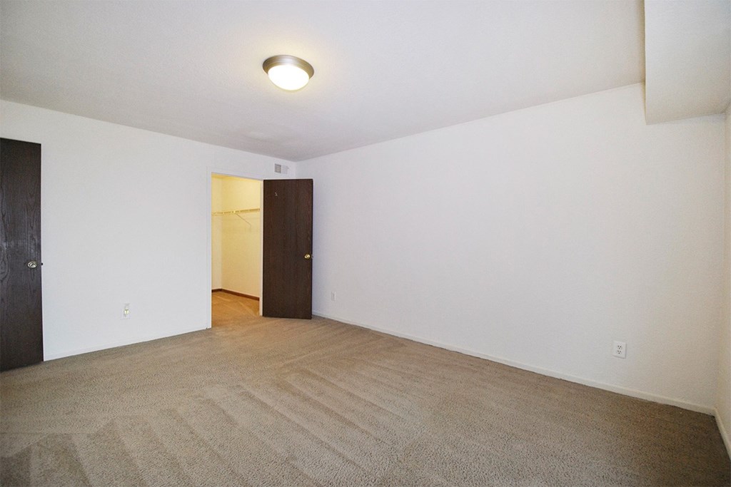 A room with a carpeted floor and two doors.