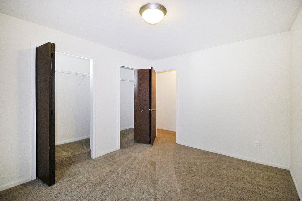 A carpeted room with a door and a mirror.