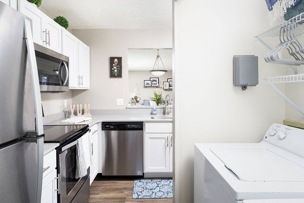 an empty kitchen with stainless steel appliances and white cabinets