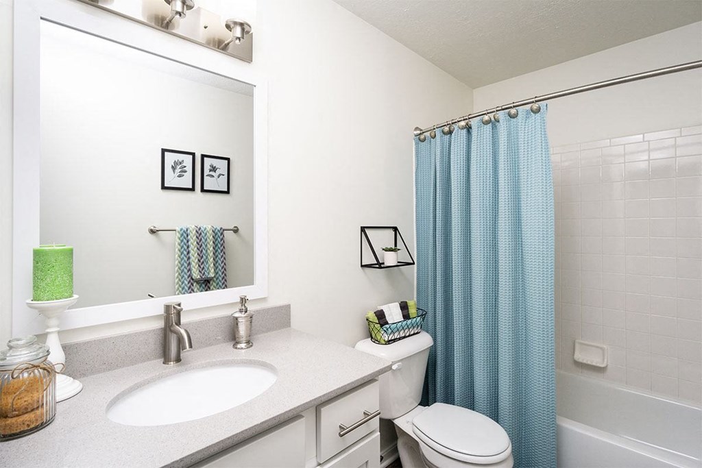 a white bathroom with a blue shower curtain