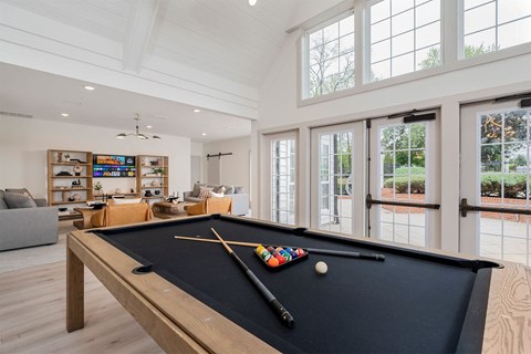 A pool table with a black cloth and a cue stick on it.