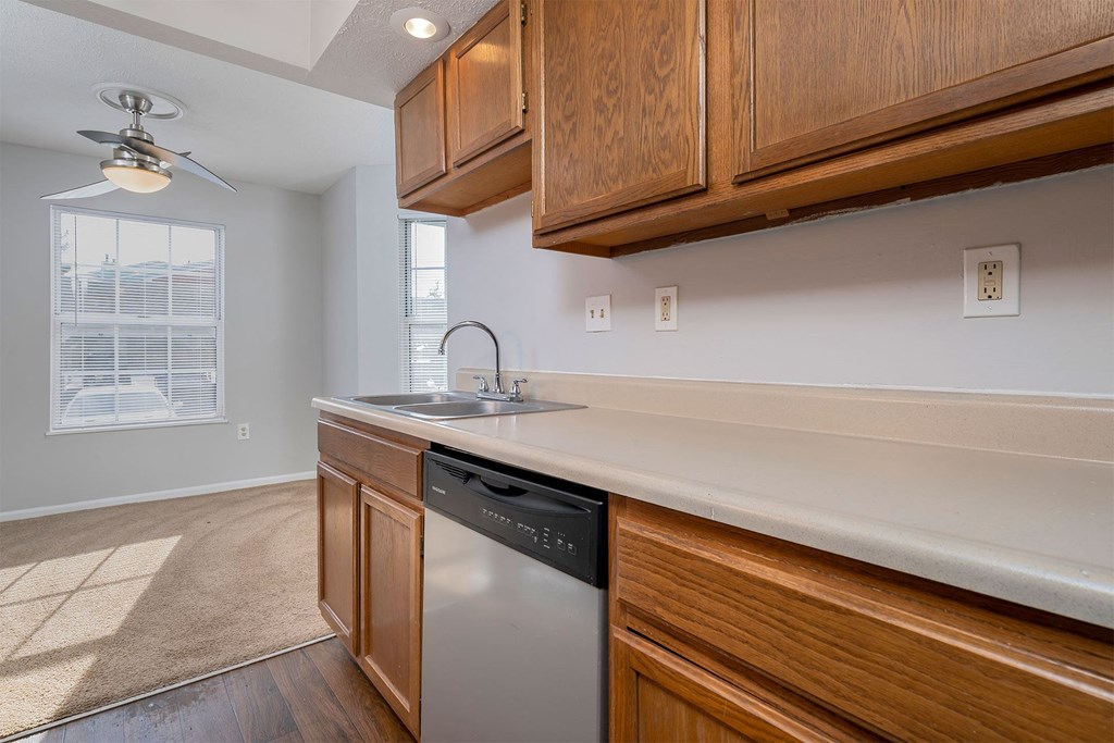 a kitchen with wooden cabinets and a dishwasher and a window