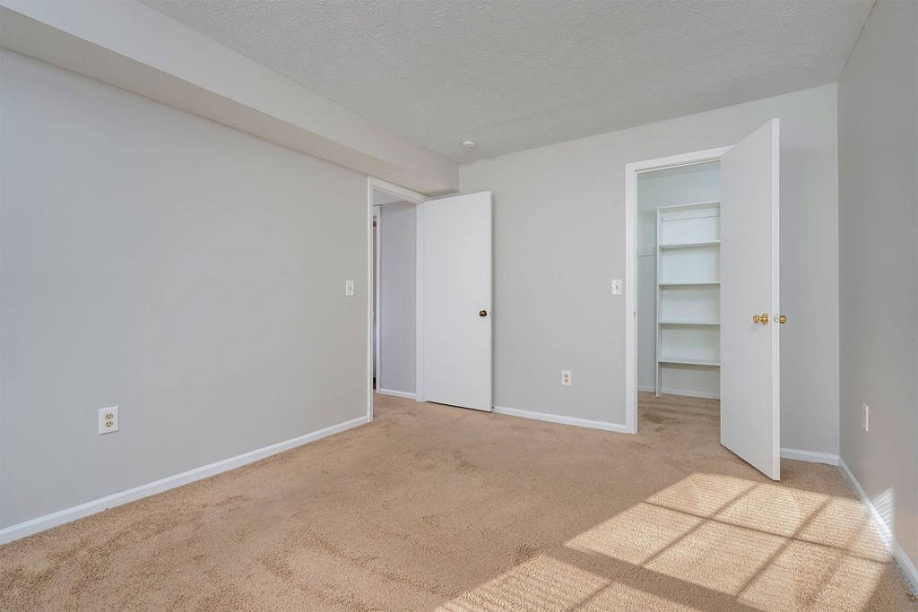 a bedroom with a carpeted floor and a closet