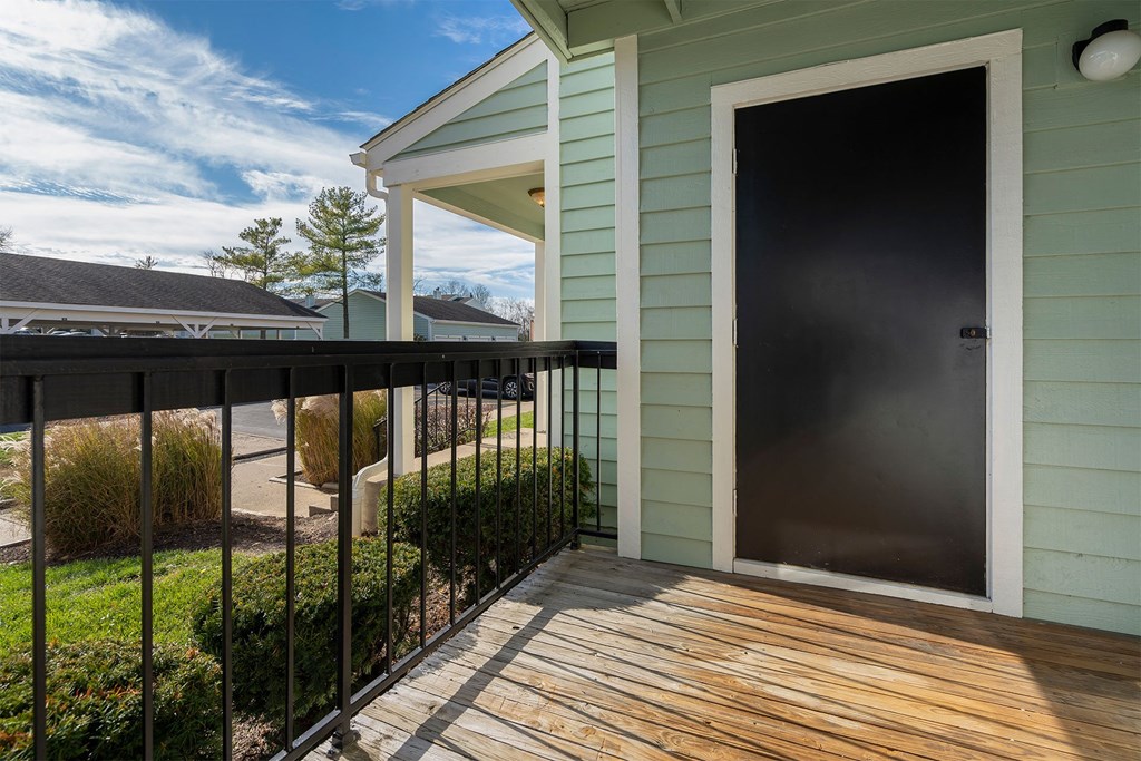 the front door of a green house with a wooden deck